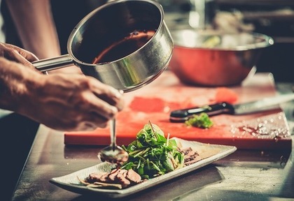 肉料理にソースをかける様子