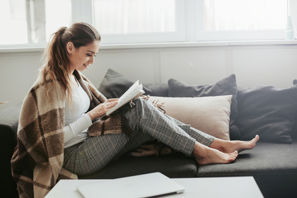 ソファに座り本を読む女性